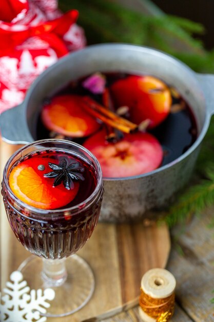 Mulled wine in a beautiful glass next to the saucepan. hot\
drink in a glass. christmas concept. family evening with a hot\
drink.