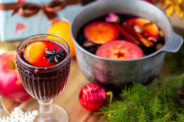 Mulled wine in a beautiful glass next to the saucepan. Hot drink in a glass. Christmas concept. Family evening with a hot drink.