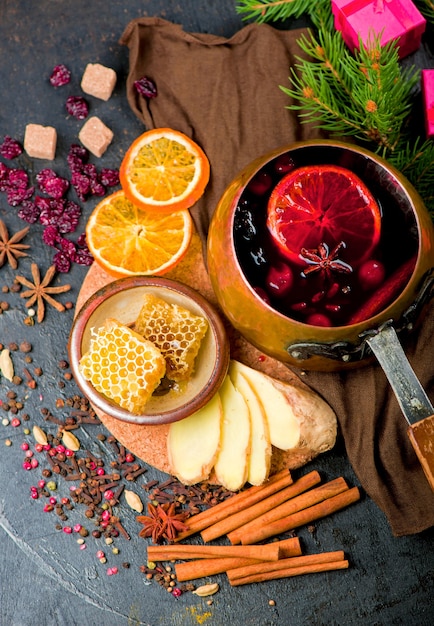 Mulled wine, blue pine tree branch and spices on wooden background.