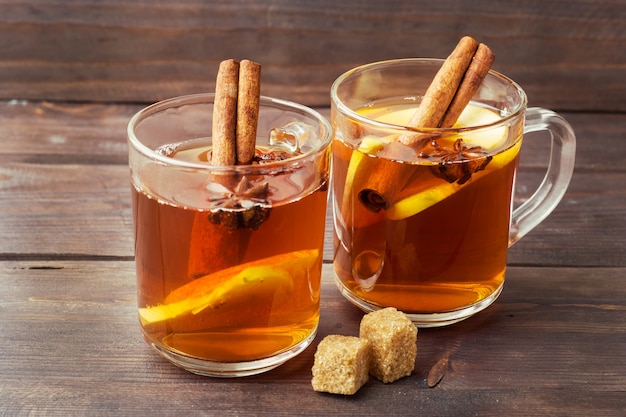 Mulled wine cider in glass mugs with cinnamon, anise and apples.