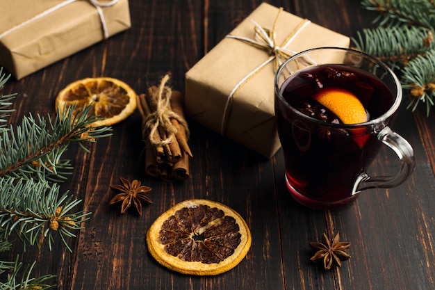 Mulled wine, a gift and spices on the table next to the tree 