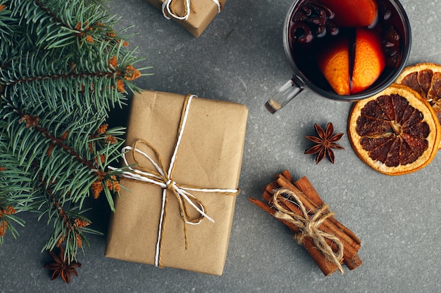 Mulled wine, a gift and spices on the table next to the tree 