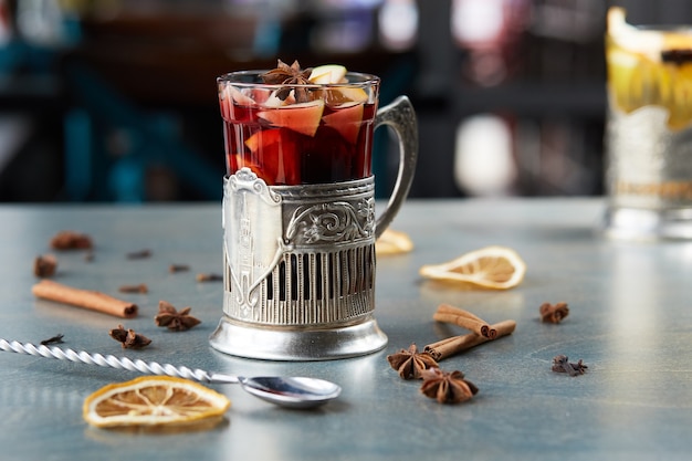 Mulled wine in a glass on a wooden table. Decorated with dark, cinnamon and lemon