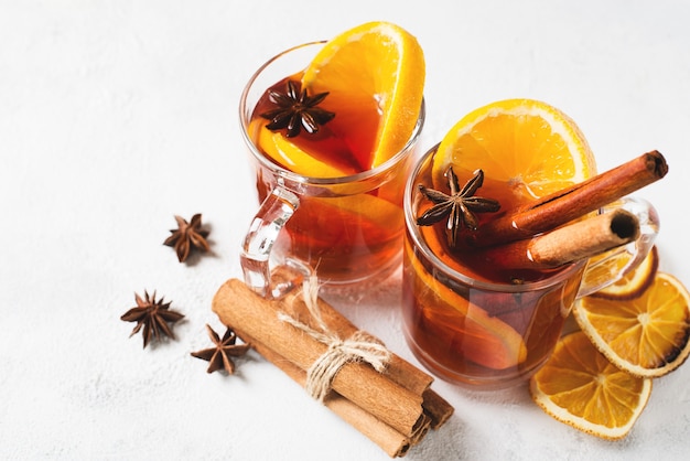 Mulled wine in glasses with orange and spices on white background
