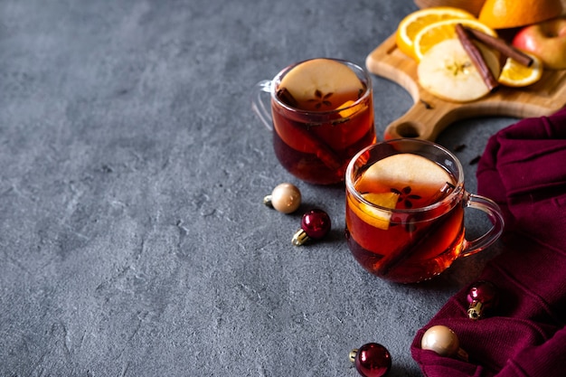 Mulled wine hot drink with citrus, apple and spices on concrete