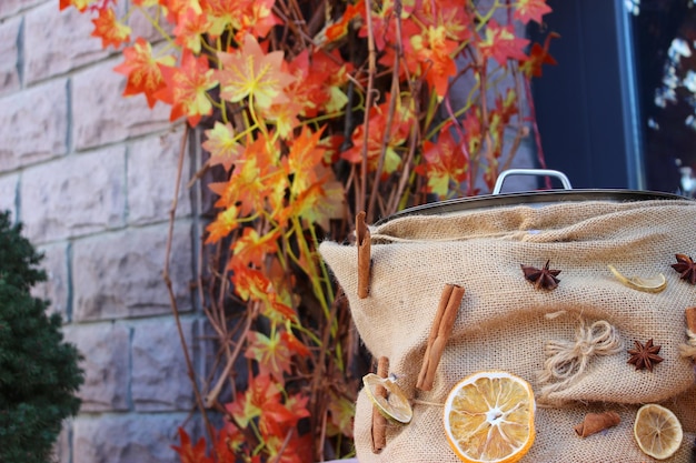 Mulled wine pan decorated with cinnamon star anise and dried oranges on background of stone wall