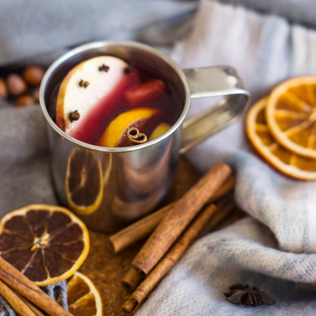 Mulled wine with apple, orange, clove, cinnamon and anise in a metal mug 