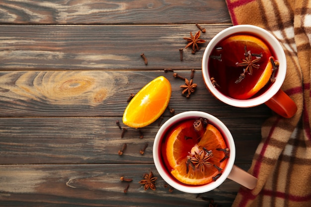 Mulled wine with cinnamon and plaid on brovn wooden background. Thanksgiving Day