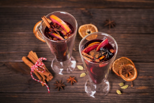 Vin brulè con frutta, bastoncini di cannella e anice su fondo di legno scuro. bevanda riscaldante invernale con ingredienti della ricetta.