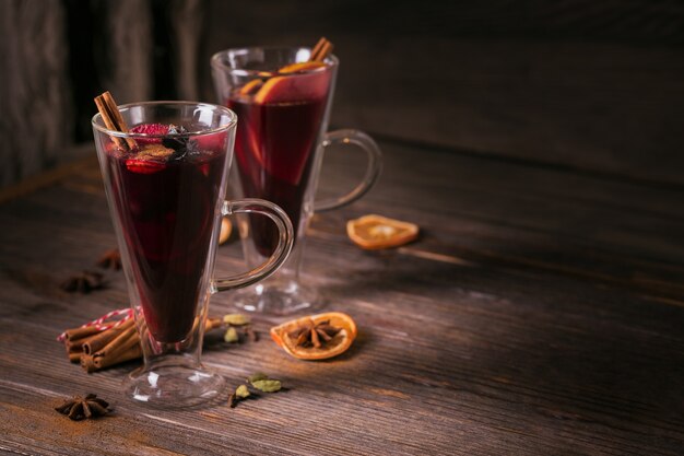 Mulled wine with fruits, cinnamon sticks and anise on dark wooden background. Winter warming drink with recipe ingredients.