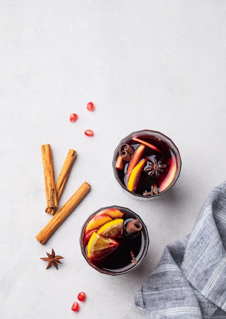 Mulled wine with orange apple and cinnamon in glasses on a light background The concept of a traditional winter hot drink with spices and fruits