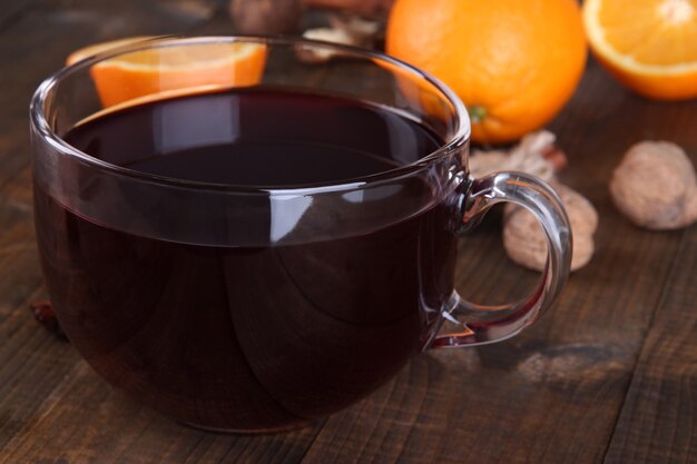 Mulled wine with orange and spices on wooden background