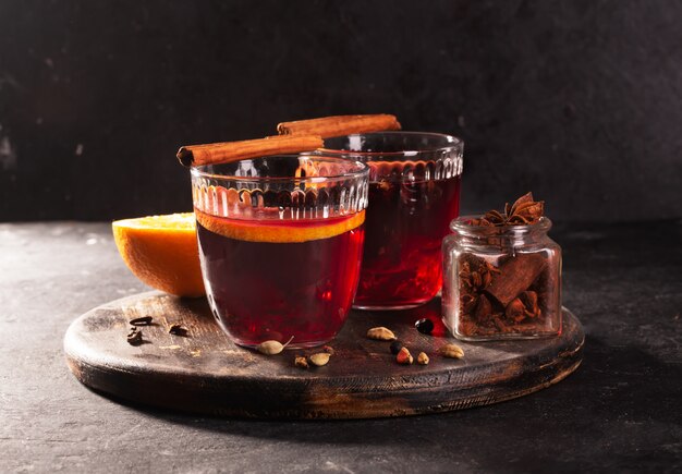 Mulled wine with slice of orange and spices on a wooden background, close up