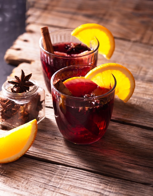 Mulled wine with slice of orange and spices on a wooden background