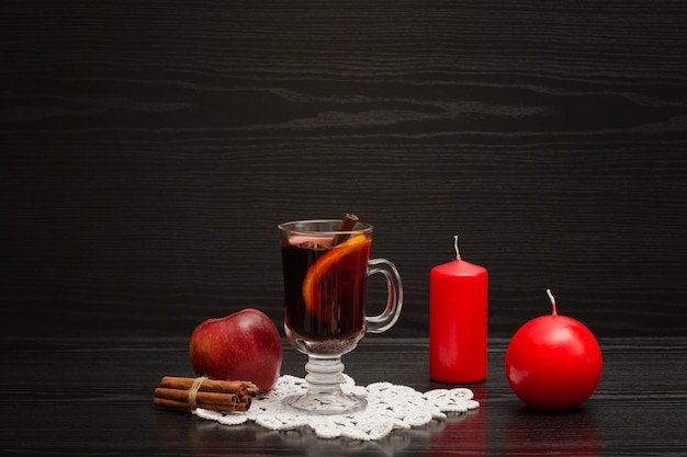 Mulled wine with spices. Candles, cinnamon sticks and apple