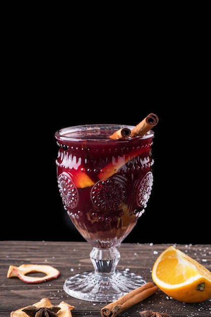 Mulled wine with spices and fruits on wooden background