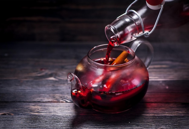 Mulled wine with spices in a glass teapot on a wooden table and space for text. Winter CHRISTMAS HOT DRINK