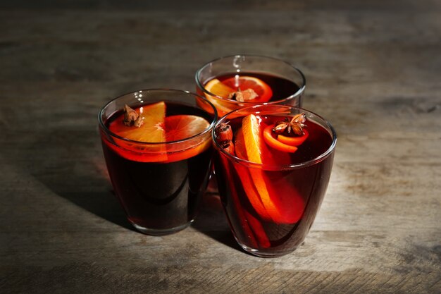 Mulled wine with spices on wooden background