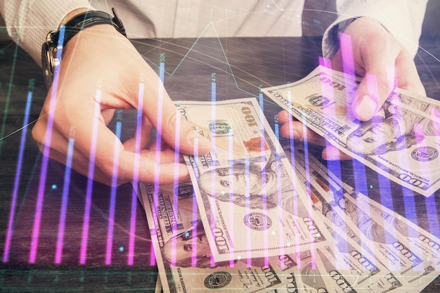 Multi-blootstelling van financiële grafiektekening hologram en Amerikaanse dollarsbiljetten en man handen Analyse concept