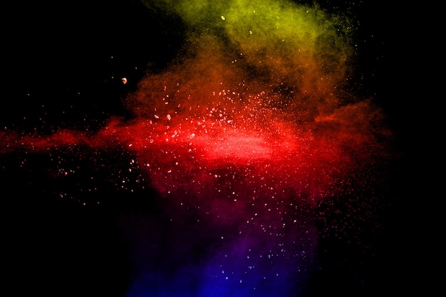 黒い背景に複数の色の粒子の爆発。暗い背景に色とりどりの埃が飛び散る。