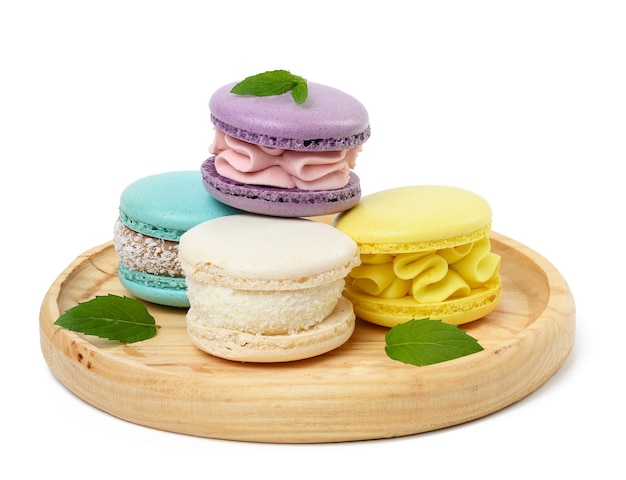 Multi colored baked macaroons on a wooden plate