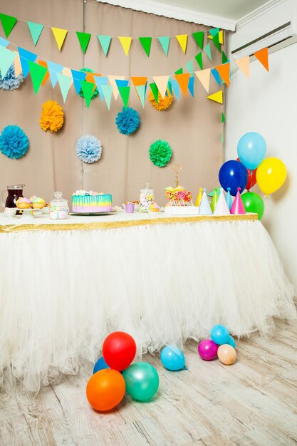 Photo multi colored balloons on table against wall at home