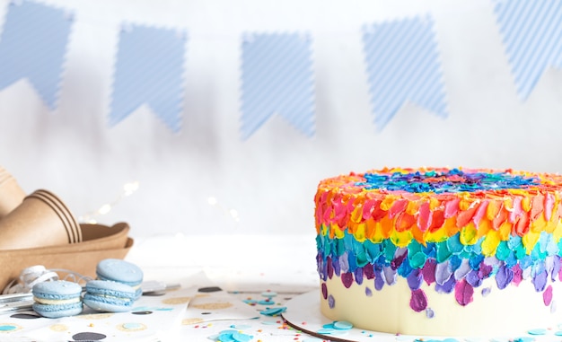 Multi-colored birthday cake decorated with cream. Birthday party concept.