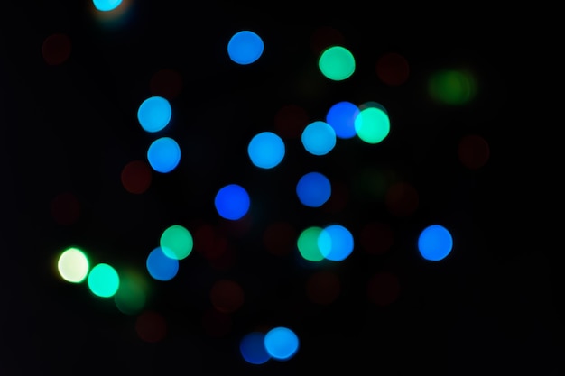 Bokeh multicolore su sfondo nero. texture sfocate luminose di luci natalizie