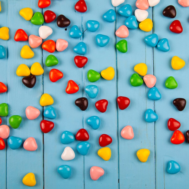 Разноцветные конфеты в форме сердца на синем деревянном фоне. День святого Валентина.