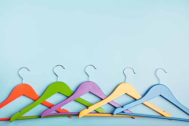 Multi-colored clothes hangers on a blue background. Concept of shopping and sale.