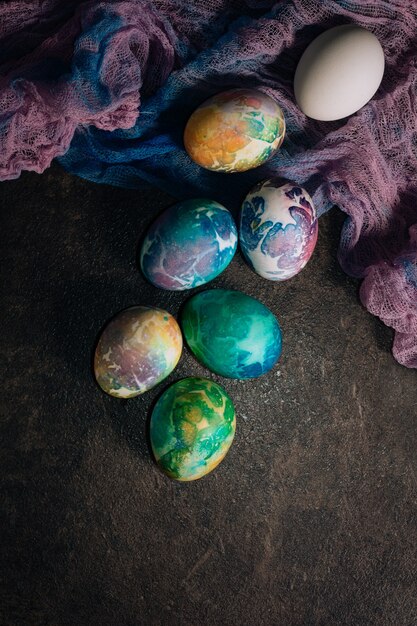 Multi-colored Easter eggs of blue tones on a multi-colored cloth background. Easter eggs in low key