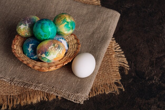 Разноцветные пасхальные яйца на фоне коричневой ткани. Пасхальные яйца крупным планом
