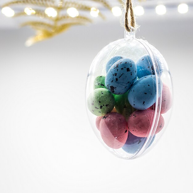 Multi-colored Easter eggs hang in glass transparent egg bauble 