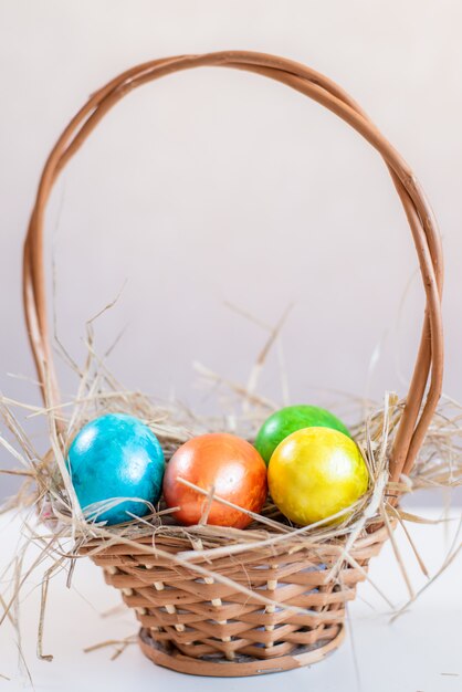 Multi-colored Easter eggs lie in a basket.