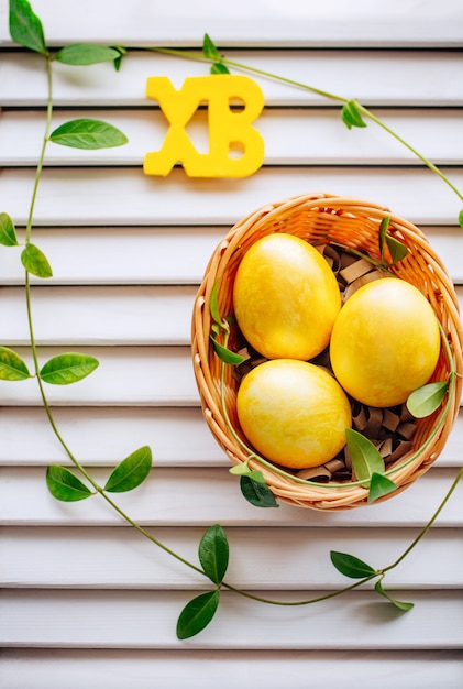 Multi-colored Easter eggs in a wicker basket on a white background.