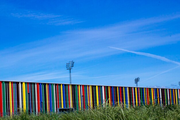 Multi colored flags on field against blue sky