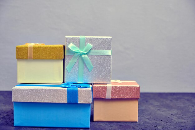 Multi colored gift boxes with bows different colors gray background