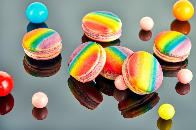 Multi colored macaron and chewing gum balls on a gray background with reflection.