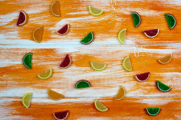 Multi-colored marmalade in the form of citrus slices scattered on an orange Board