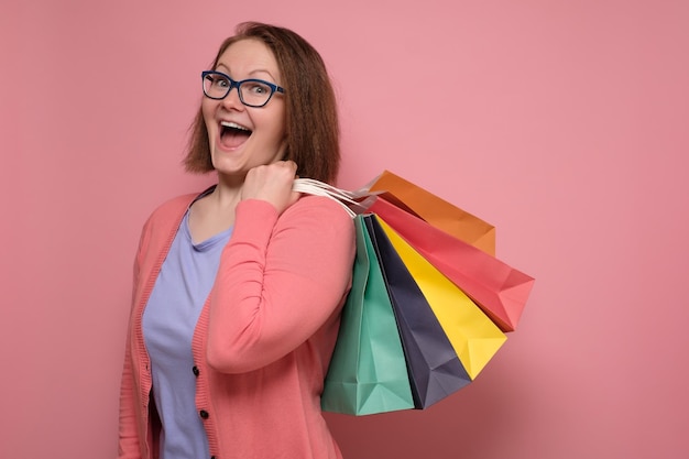 Multi colored packages young woman in pink colored aftershopping being excited