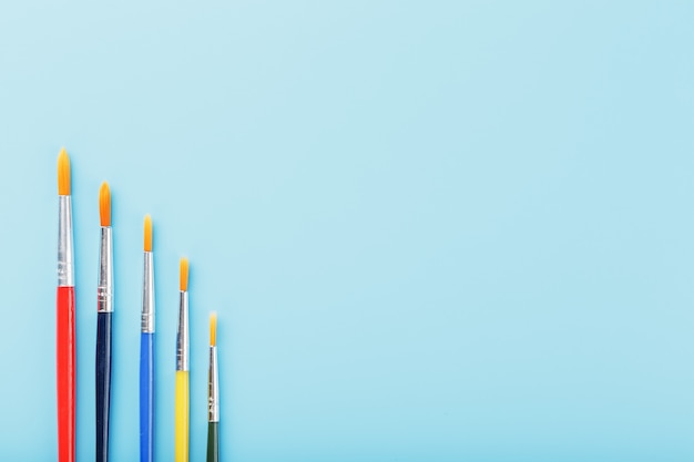 Multi-colored paint Brushes on a blue background.