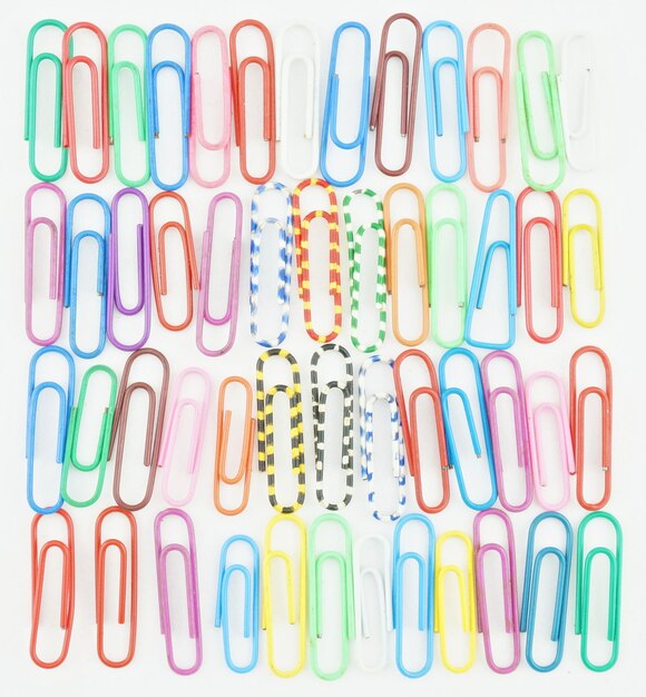 Multi colored paper clips arranged over white background