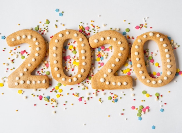 Guarnizione e pan di zenzero colorati multi zucchero della pasticceria sotto forma di numeri 2020 su un fondo bianco