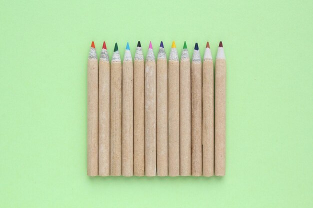 Photo multi colored pencils isolated on green background back to school concept sketching and drawing ho