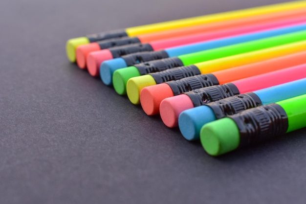 Multi colored pencils with rubber eraser on the black background.