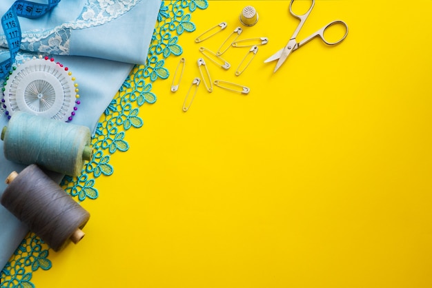 Multi-colored reels with sewing threads, meter tape, scissors on a bright background. Flat lay