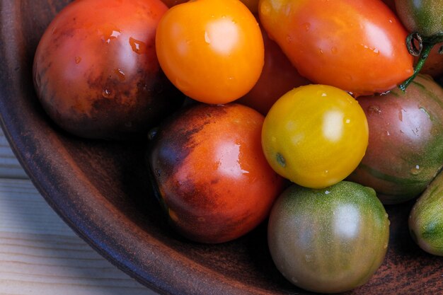 Multi-colored ripe small tomatoes of different varieties lie on a wooden table close-up macro photography