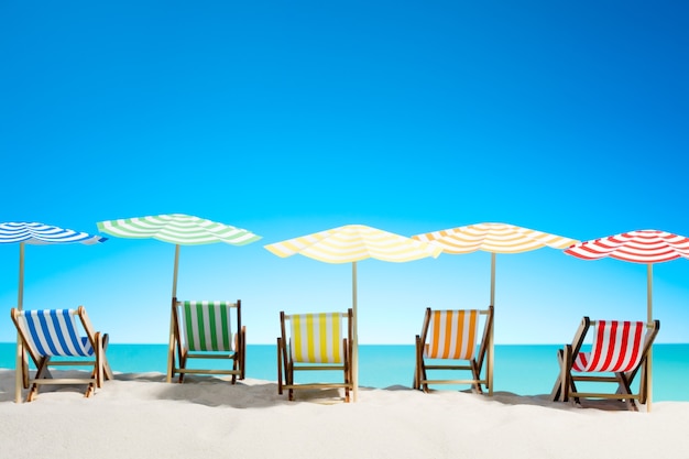Multi-colored sun loungers with umbrellas on the sandy beach, sky with copy space