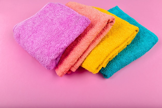 Multi-colored towels on a pink space. pink, beige, yellow and blue flower towels. place for writing. house order