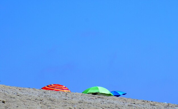 Multi colored umbrellas on beach against clear blue sky